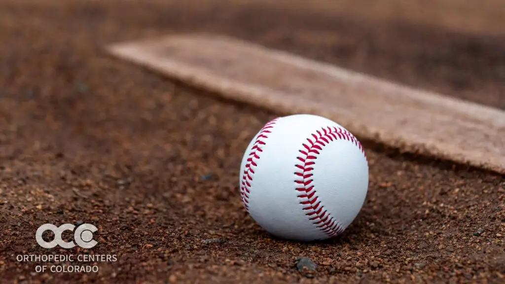 Baseball on a pitcher’s mound representing Tommy John surgery and throwing athlete elbow injuries